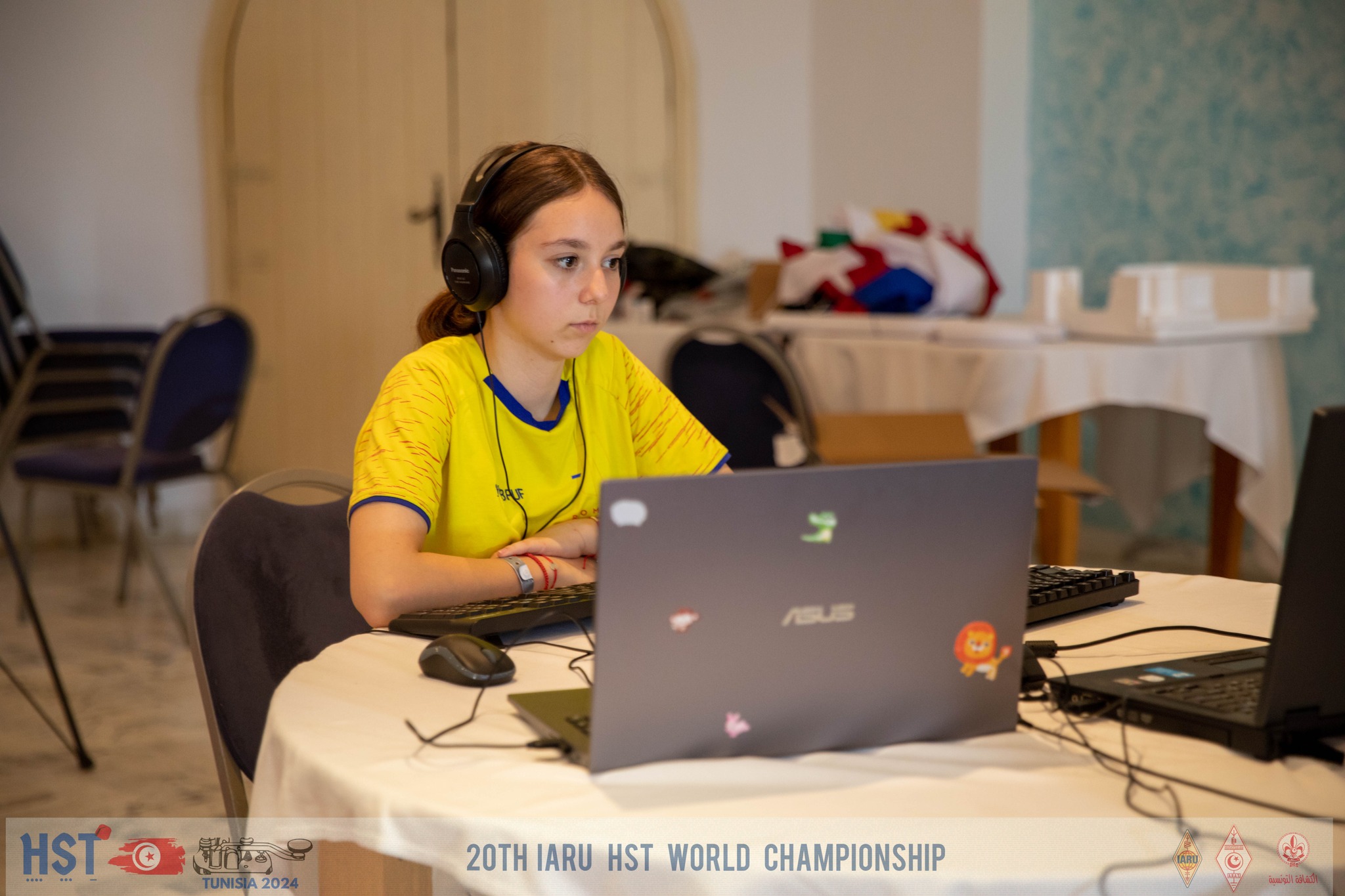 Archivo JPG, de una concursante con audífonos y frente a una computadora