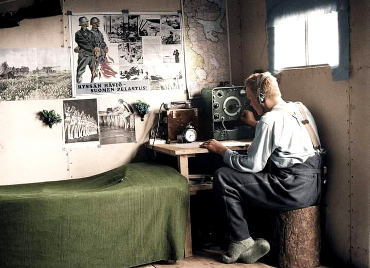 Archivo JPG de una fotografía antigua donde se ve una persona en una cabaña con un radio de bulbos sintonizando y audífonos